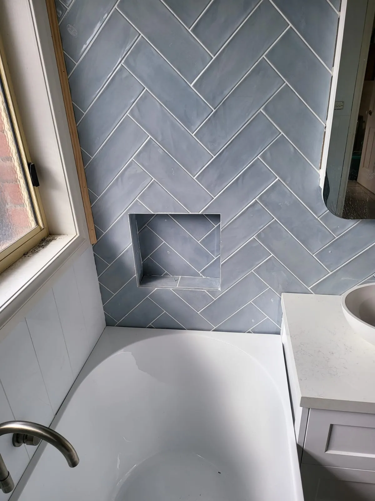 Blue-grey herringbone feature wall tile with a built-in shelf