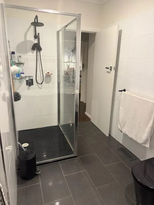 Original Newcomb shower zone before renovation with a framed screen and partial tiling