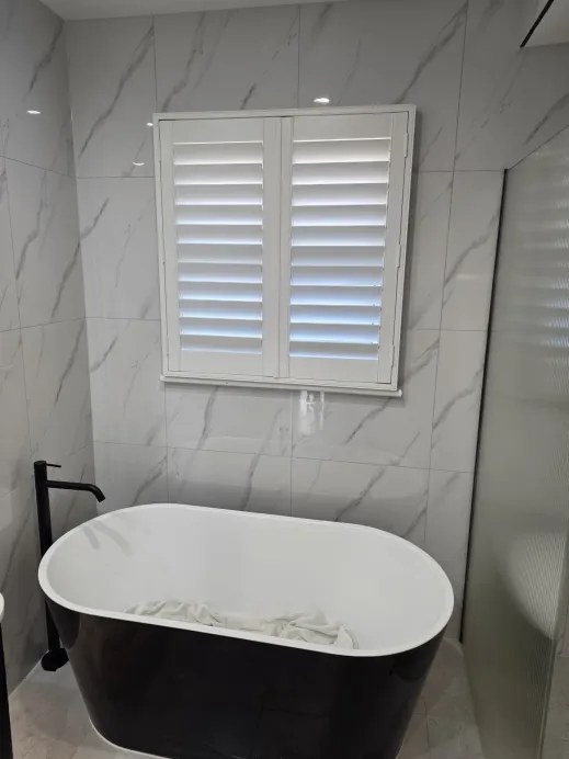 Black freestanding bath against the marble tile wall