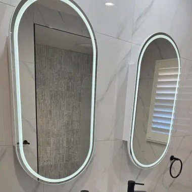 Backlit oval LED mirrors above the vanity